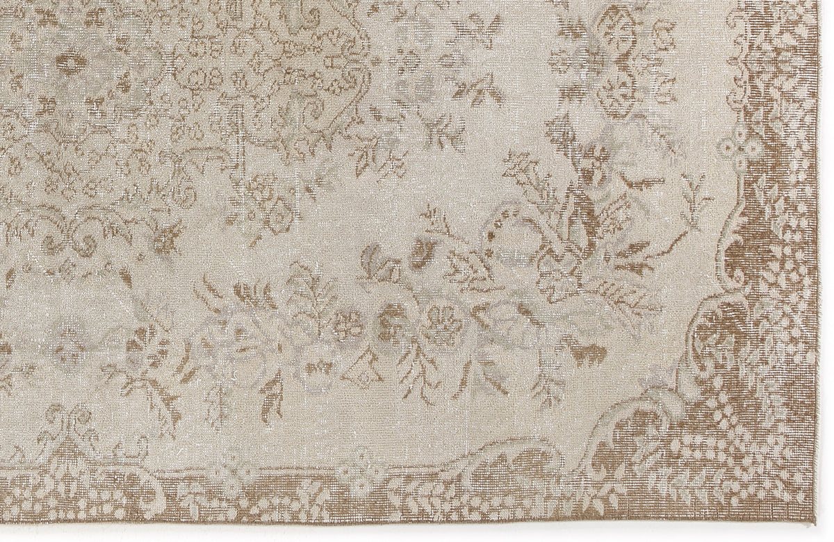 Beige and taupe rug with a distressed traditional floral medallion pattern and a decorative border.