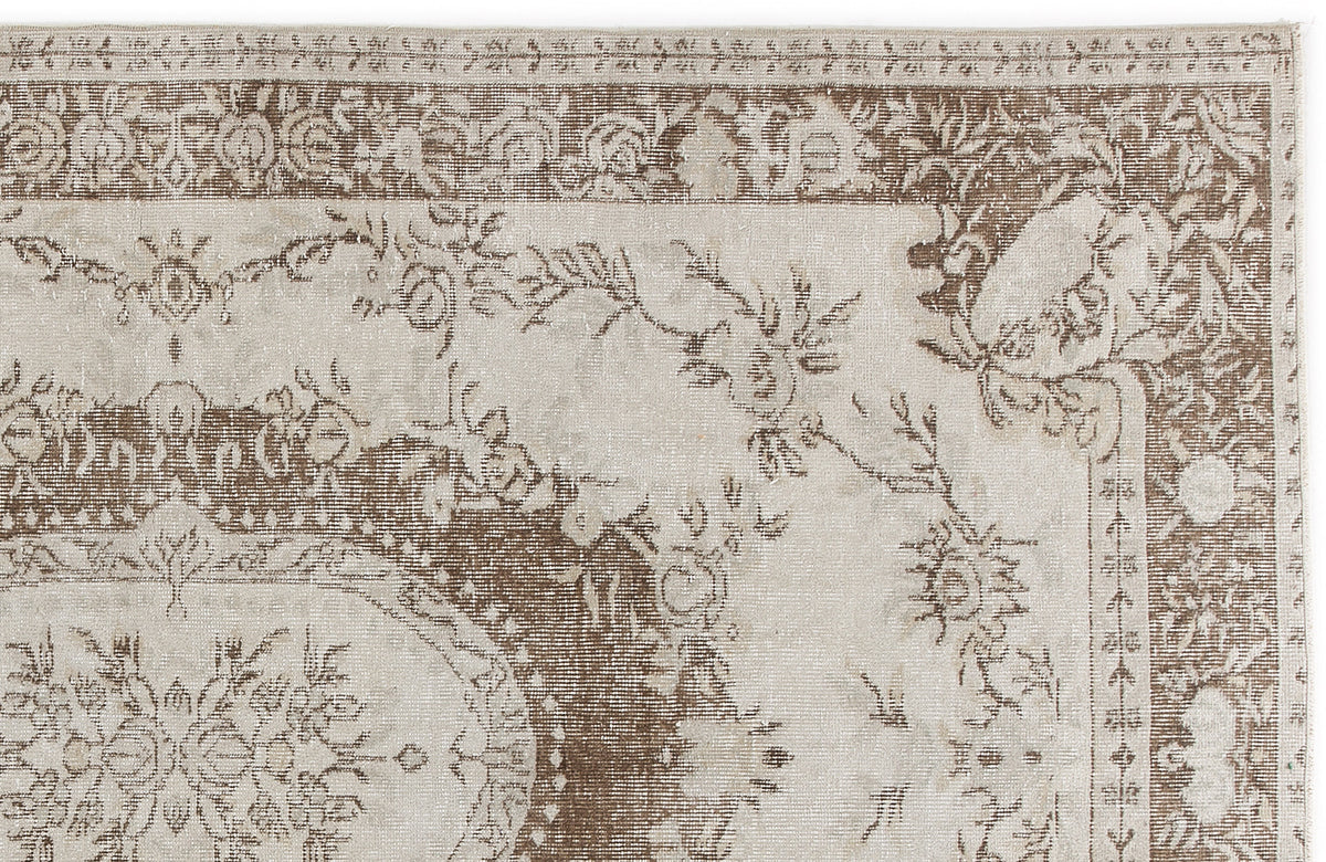 Beige and brown traditional rug with a distressed floral medallion pattern and ornate border.