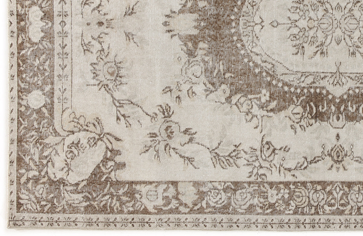 Beige and brown traditional rug with a distressed floral medallion pattern and ornate border.