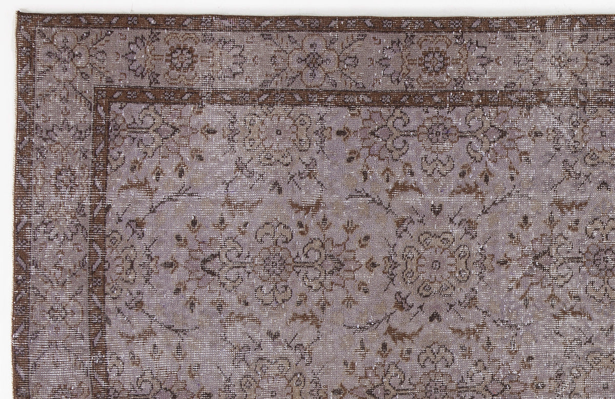 Distressed lavender and brown rug with a traditional floral medallion pattern and a decorative border.