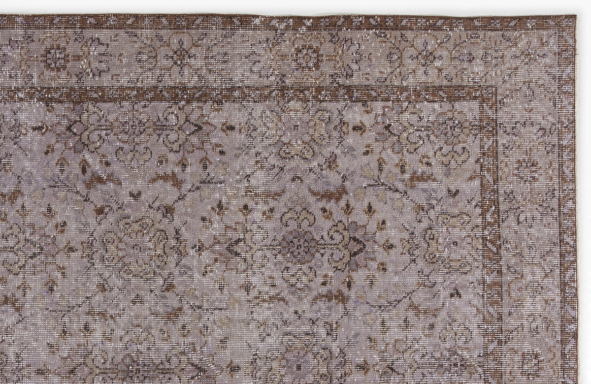 Distressed taupe and brown rug with a traditional floral medallion pattern and a detailed geometric border.