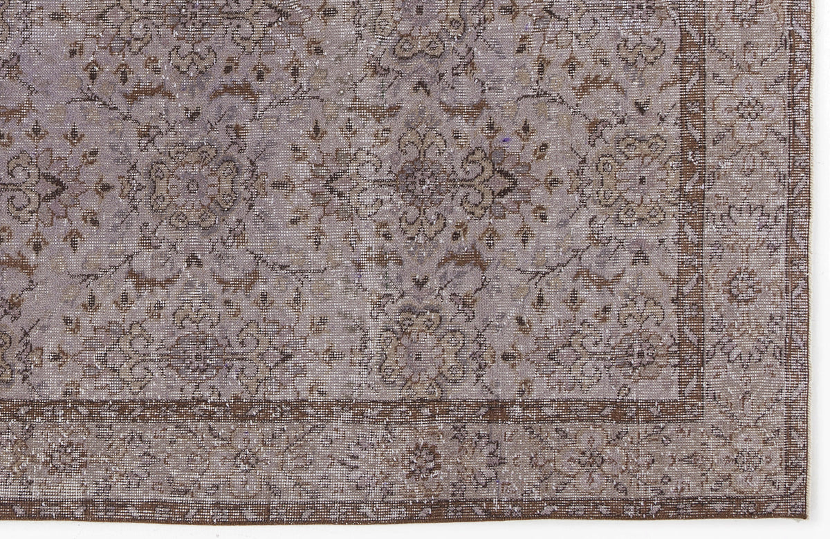 Distressed lavender and brown rug with a traditional floral medallion pattern and a wide decorative border.