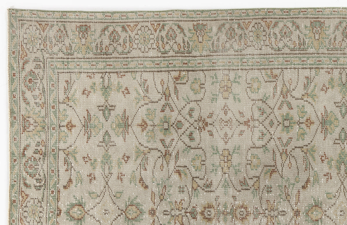 Beige rug with a faded traditional floral medallion pattern in sage green, rust, and gold on a white background.