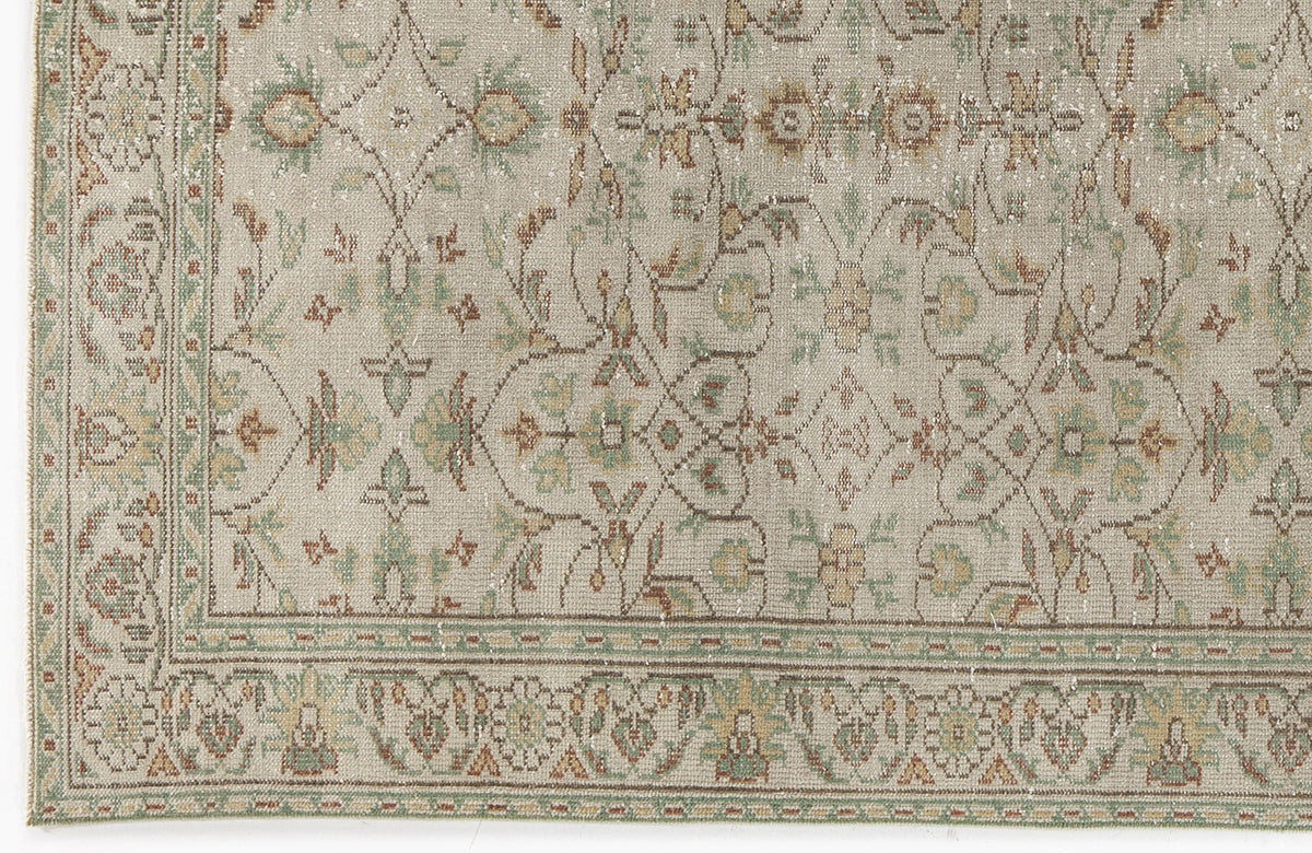 Beige rug with a distressed traditional floral medallion pattern in muted green, brown, and cream tones.
