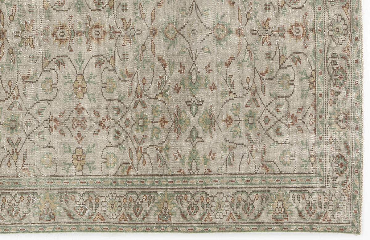 Beige rug with a distressed traditional floral medallion pattern in muted green, rust, and gold tones.