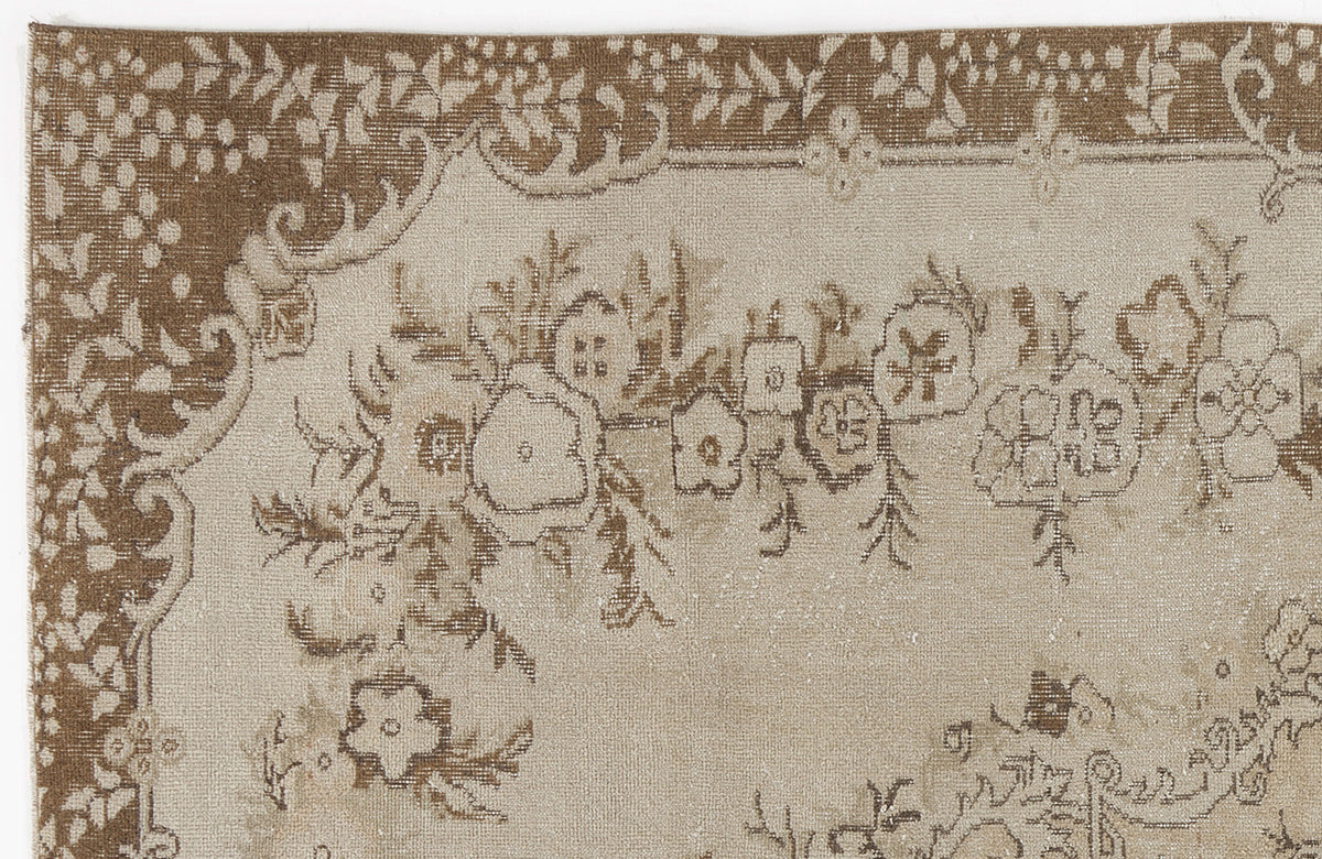Beige and brown rug with a distressed floral pattern and a decorative border.
