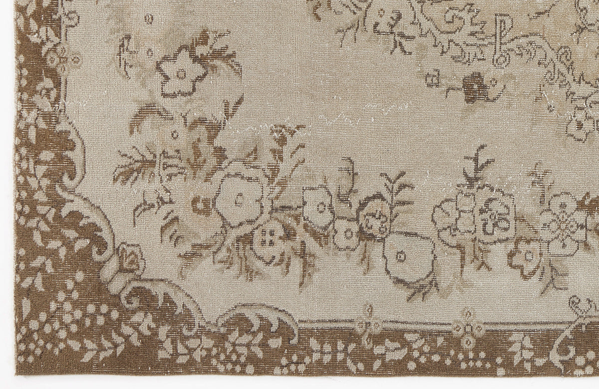 Beige and brown vintage-style rug with a distressed floral medallion pattern and decorative border.
