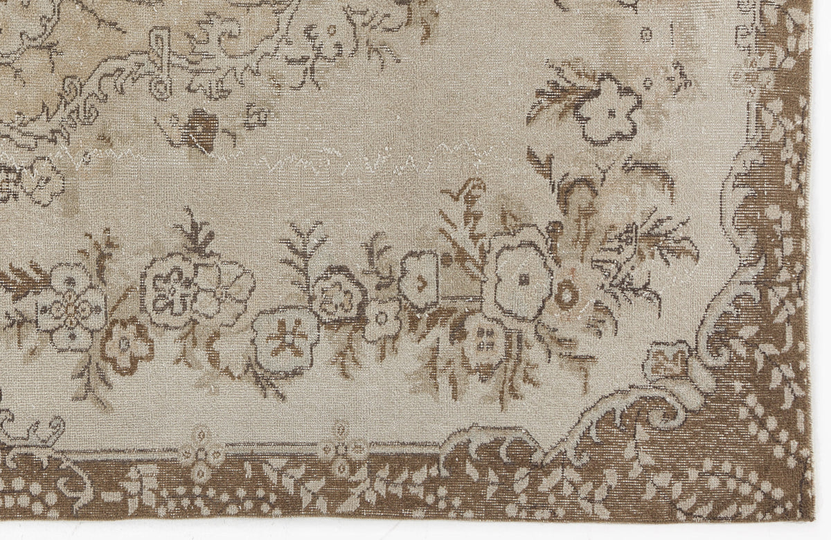 Beige and brown rug with a distressed floral pattern and a decorative border.