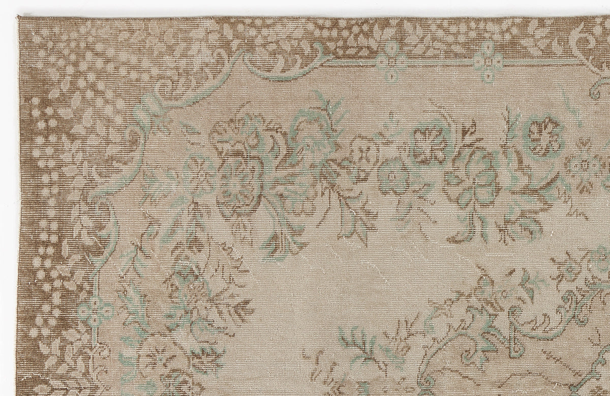 Beige and brown vintage-style rug with a faded floral pattern and soft teal accents.