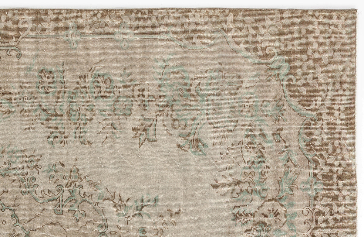 Beige and brown traditional rug with a faded floral medallion pattern and soft teal accents.