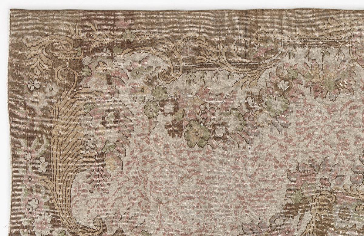 Brown, beige, and muted pink vintage-style rug with a detailed floral border and intricate botanical pattern.