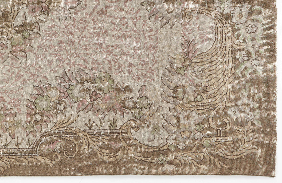 Beige and brown vintage-style rug with a faded floral medallion pattern and intricate scrollwork border.