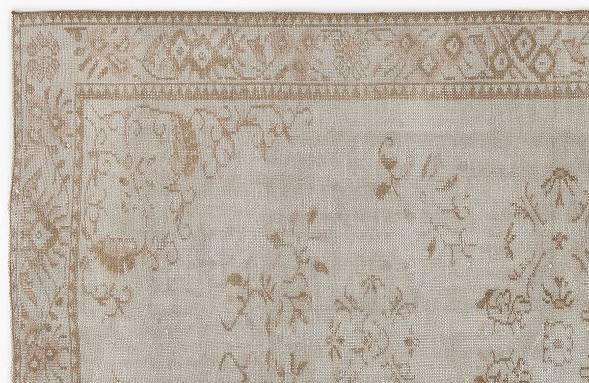 Beige and tan vintage-style rug with a faded floral border and scattered botanical motifs.