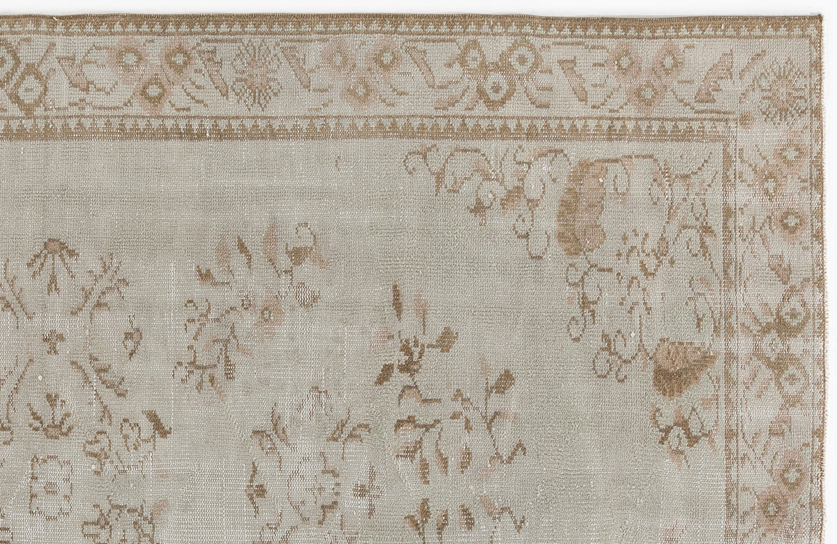 Light gray and tan vintage-style rug with a faded floral medallion pattern and a decorative geometric border.