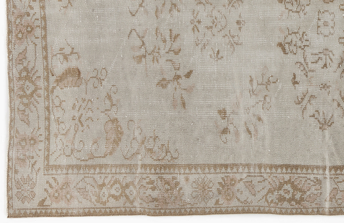 Beige and taupe distressed rug with a faded traditional floral pattern and a decorative border.