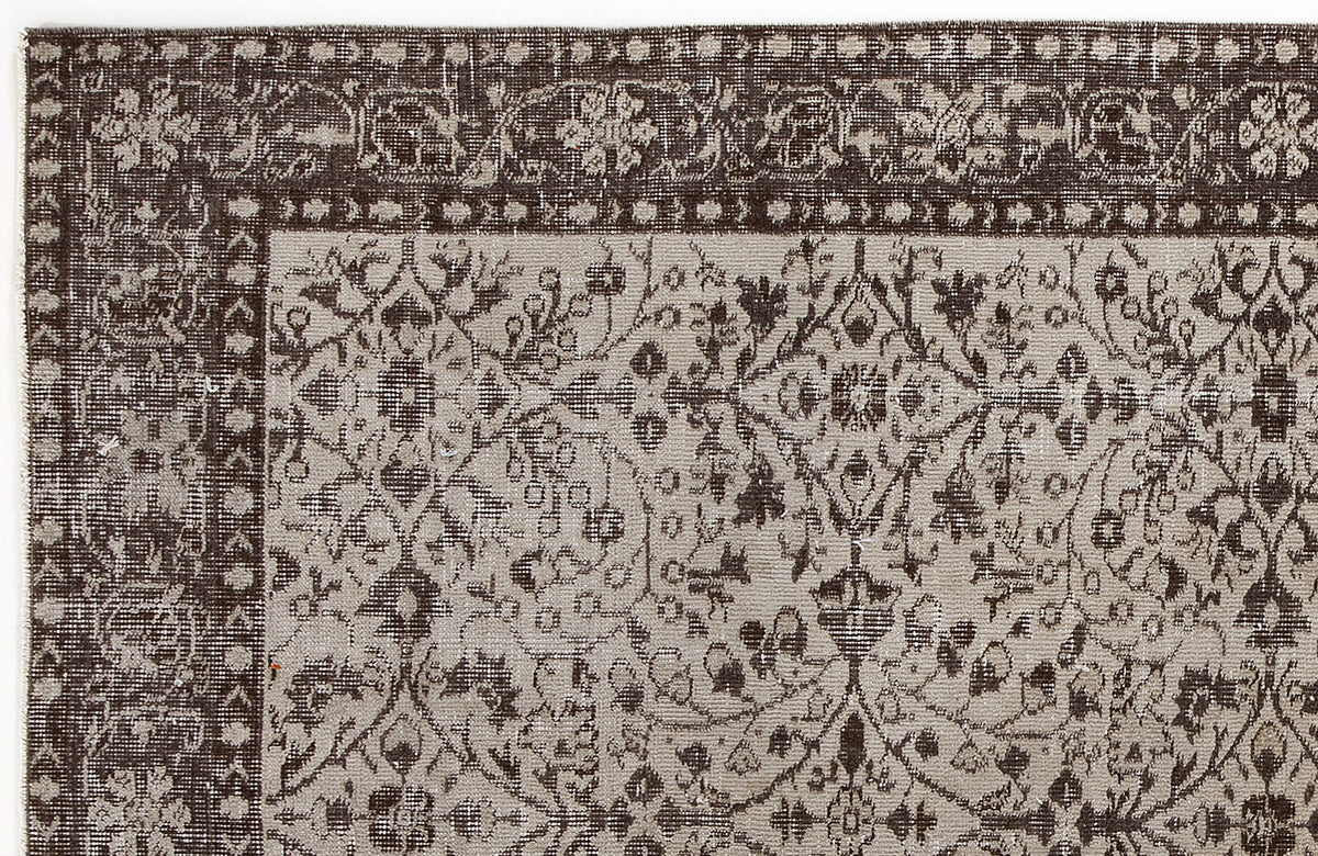 Dark brown and beige vintage-style rug with a distressed floral medallion pattern and a wide decorative border.