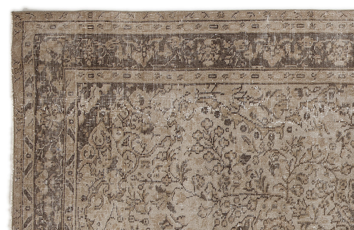 Distressed brown and beige rug with a traditional floral medallion pattern and a detailed border.
