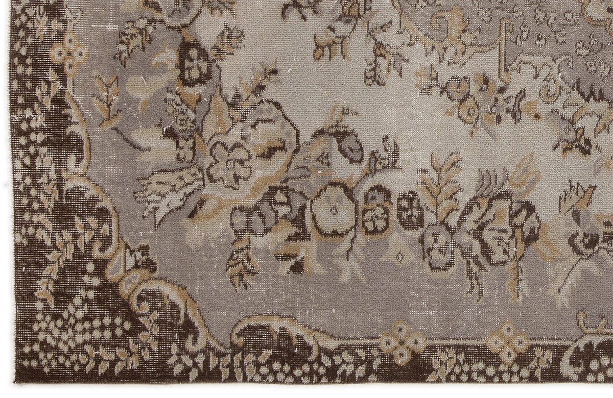Distressed grey and brown rug with a traditional floral medallion pattern and ornate border.