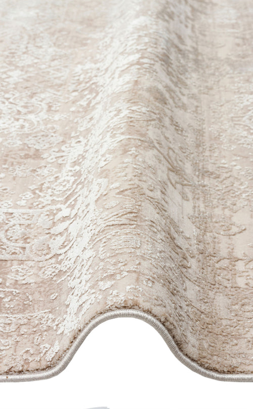 Bild 1 in Galerieansicht laden. Beige and cream rug with a distressed traditional medallion pattern, shown folded to reveal the texture and bound edge.