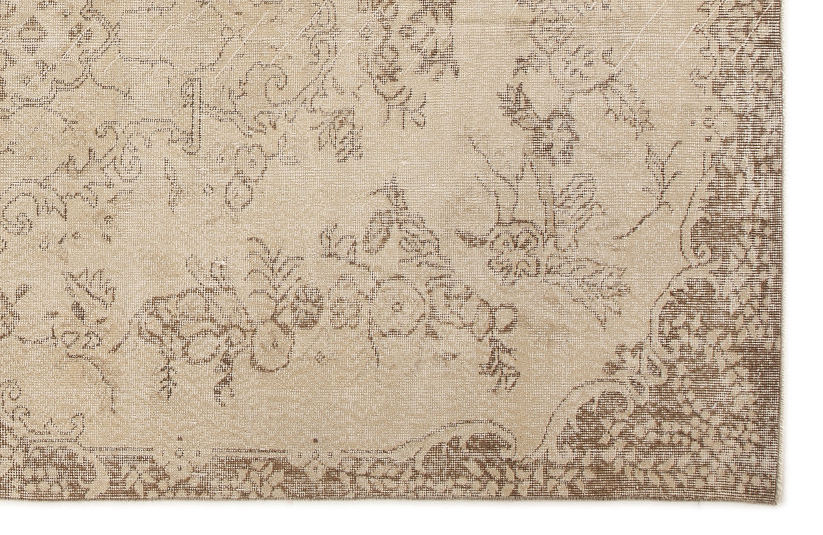 Beige and brown rug with a faded, distressed floral pattern and a decorative border.
