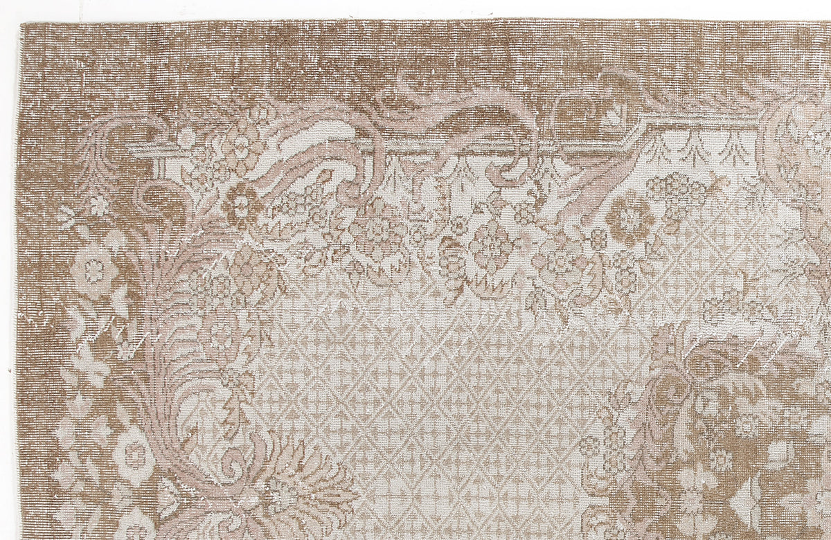 Distressed beige and cream rug with a traditional floral medallion pattern and a geometric lattice border.