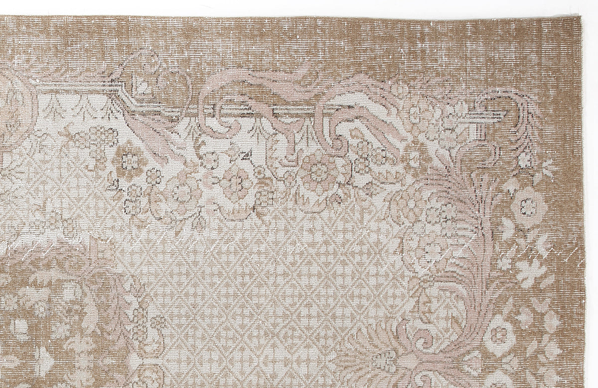 Tan and cream vintage-style rug with a distressed floral medallion pattern and a geometric lattice border.