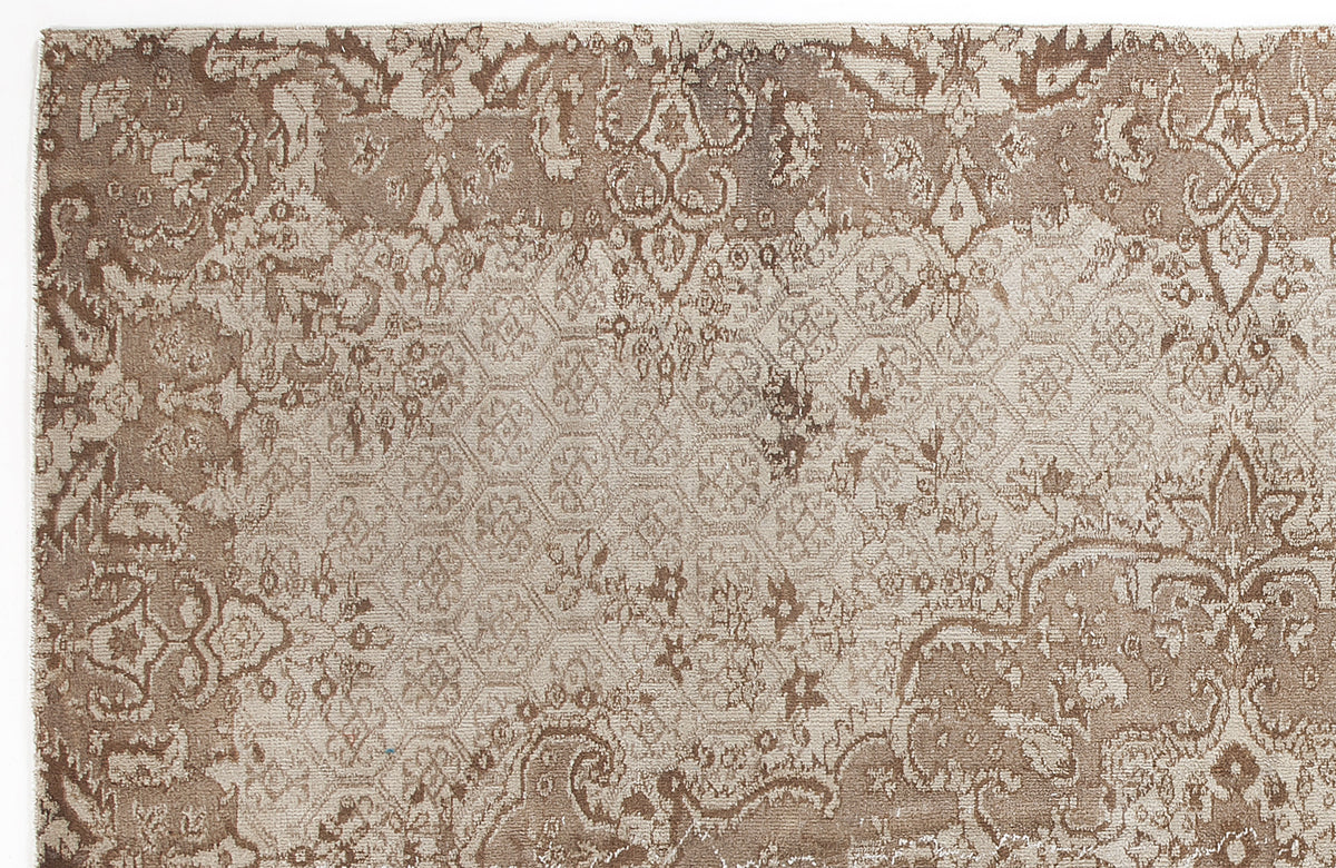 Taupe and beige rug with a distressed, layered pattern featuring traditional floral motifs and a geometric honeycomb grid.