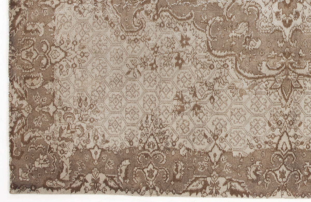 Taupe and beige rug with a distressed traditional floral medallion pattern and a geometric honeycomb center.