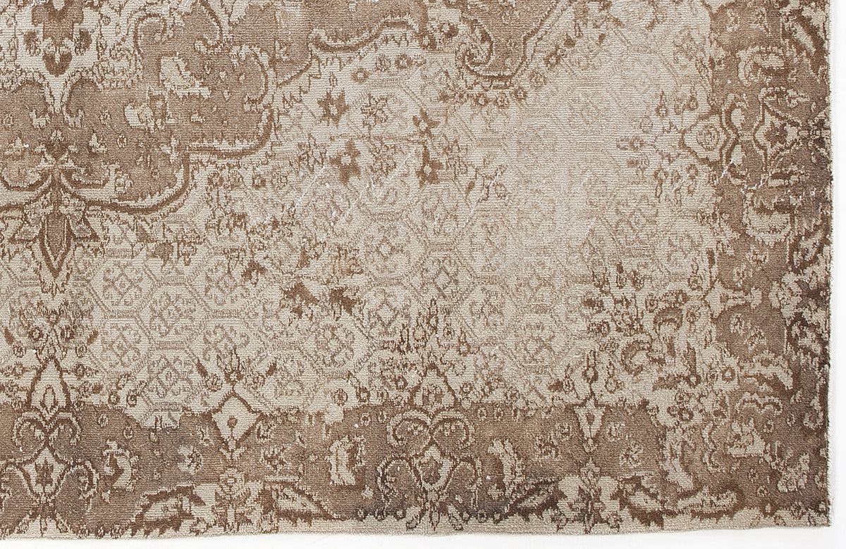 Taupe and beige rug with a distressed, traditional floral medallion pattern and faded geometric details.