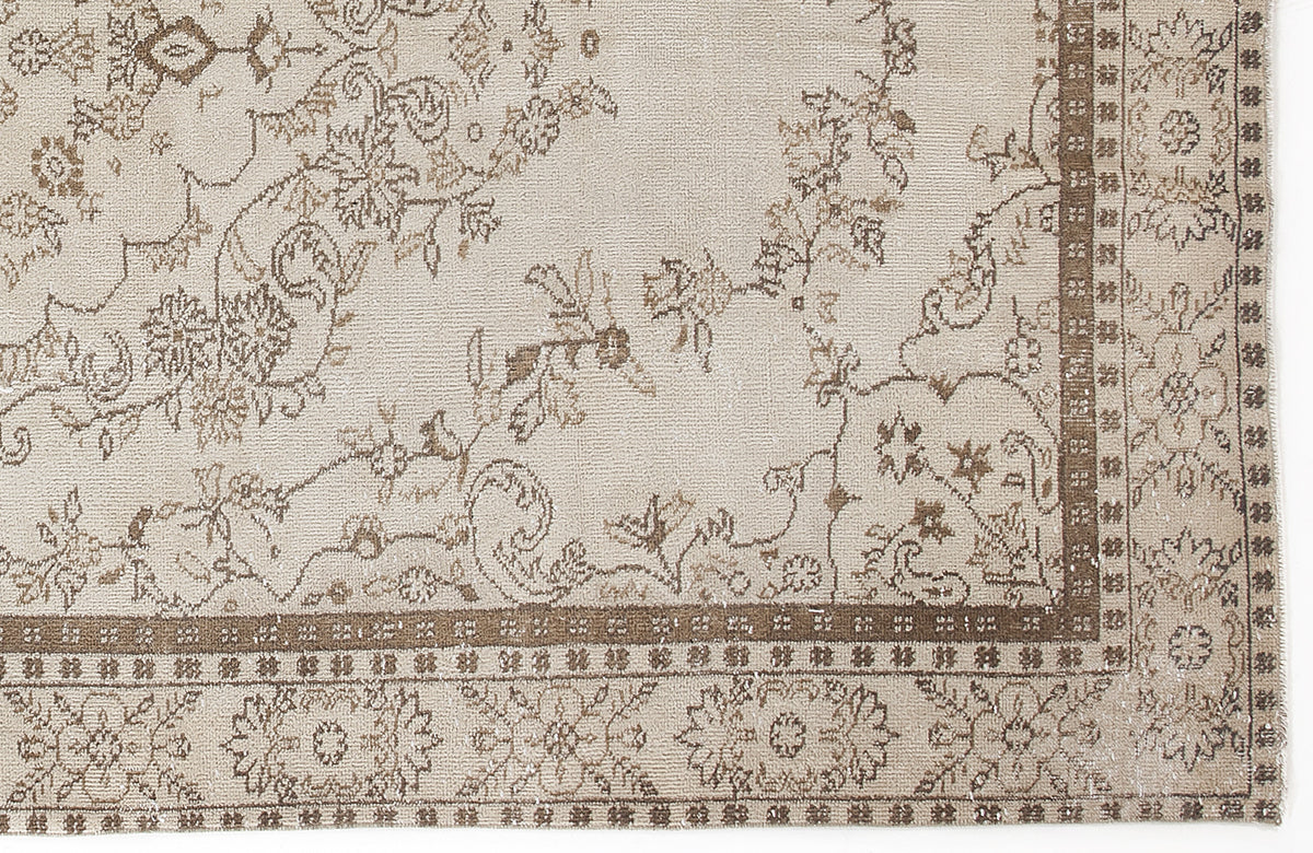 Beige and brown rug with a traditional floral vine pattern and a geometric border on a white background.