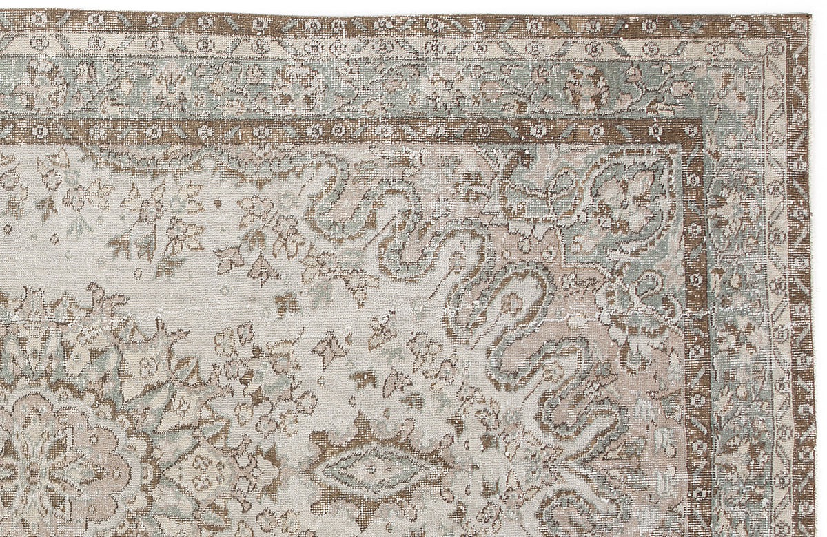 Distressed traditional rug in cream, sage green, and brown with a floral medallion pattern and ornate border.