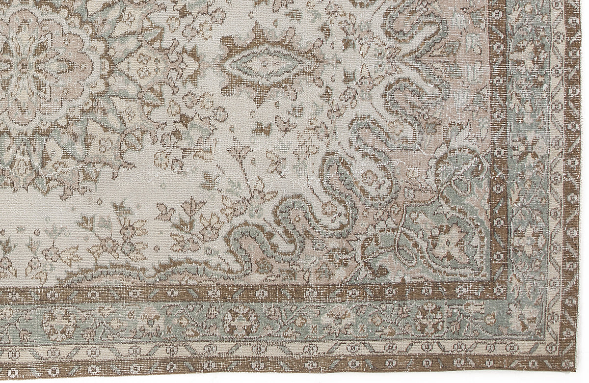 Distressed traditional rug with a cream, sage green, and brown floral medallion pattern and a detailed border.