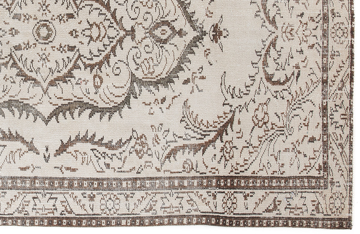 Cream and brown rug with a distressed traditional floral medallion pattern and a geometric border.