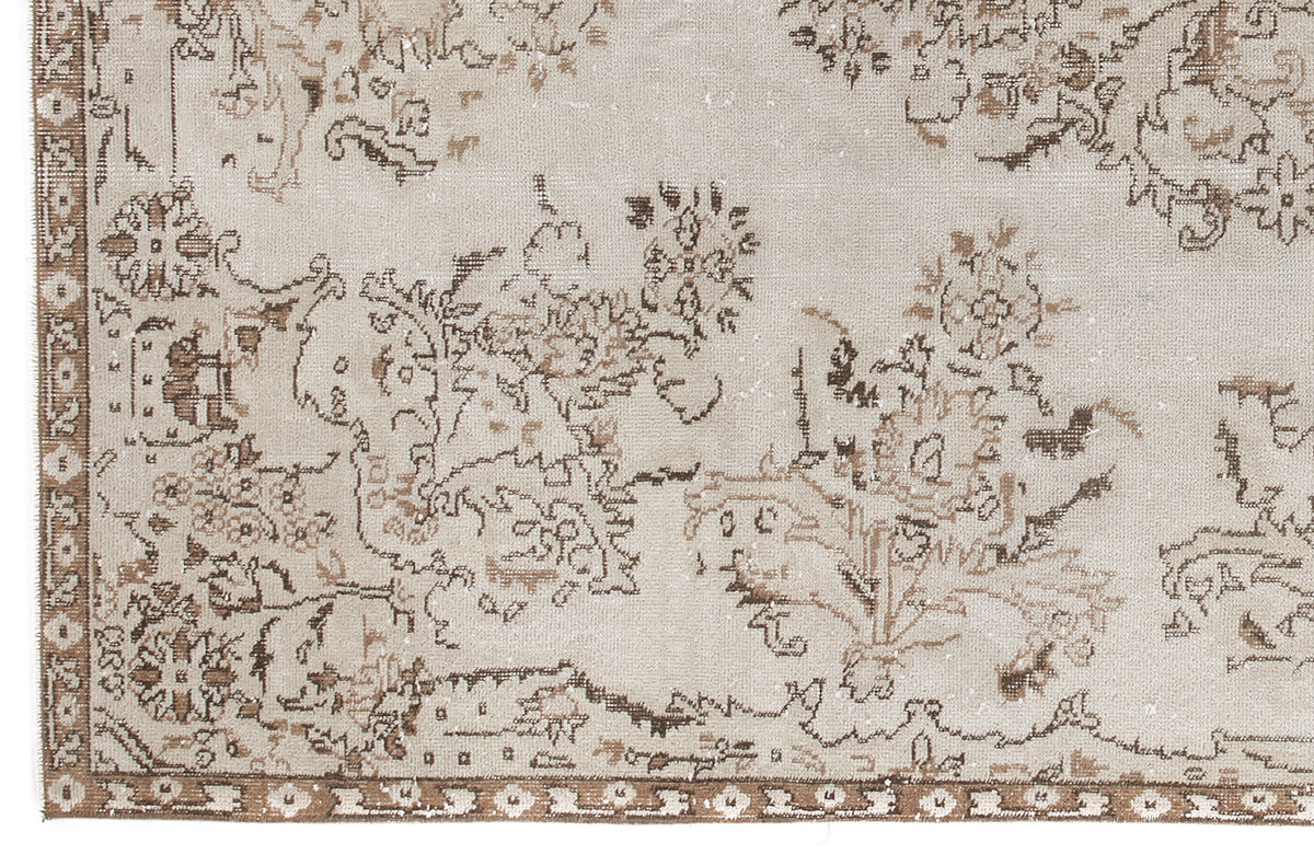 Beige and brown distressed rug with a faded floral medallion pattern and a geometric border.