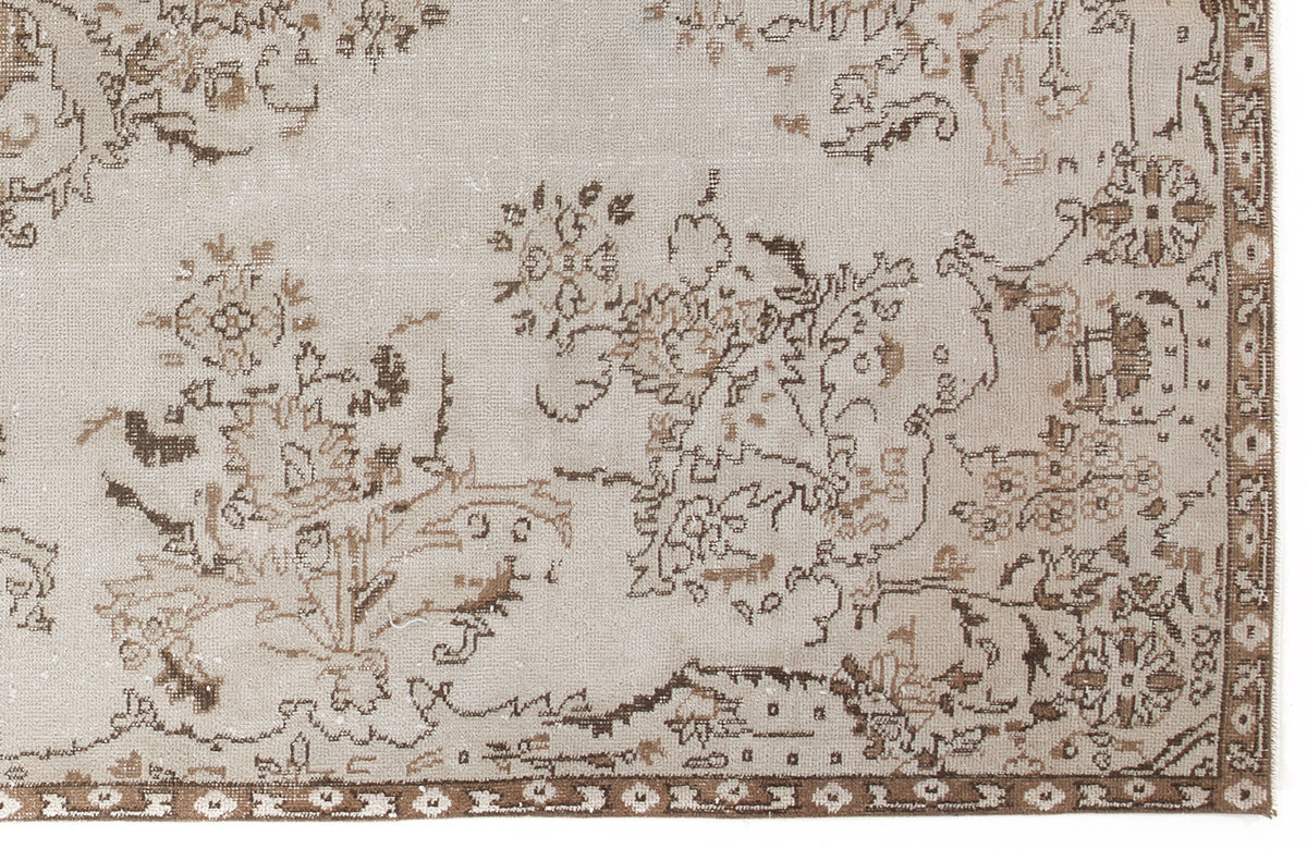 Beige and brown distressed rug with a faded floral medallion pattern and a decorative border.