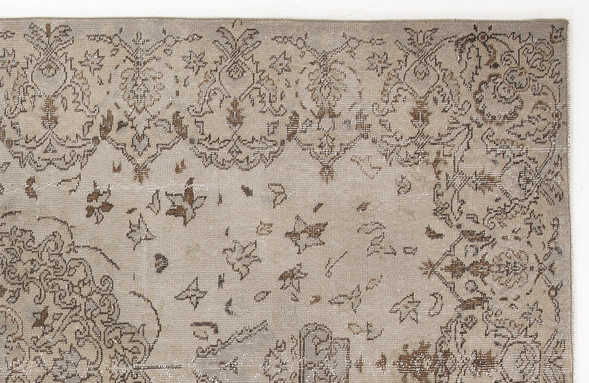Taupe and brown distressed rug with a traditional floral medallion pattern and scattered botanical motifs.