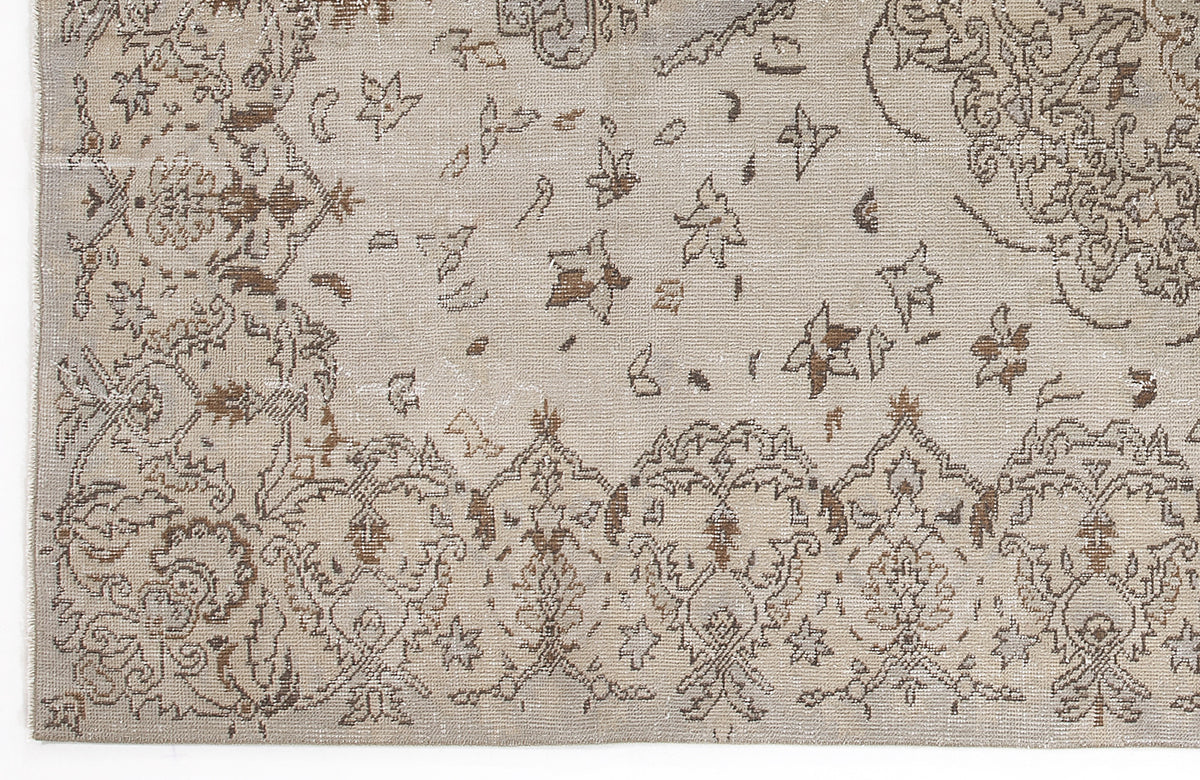 Beige and brown distressed rug with a traditional floral medallion pattern and scattered botanical motifs.