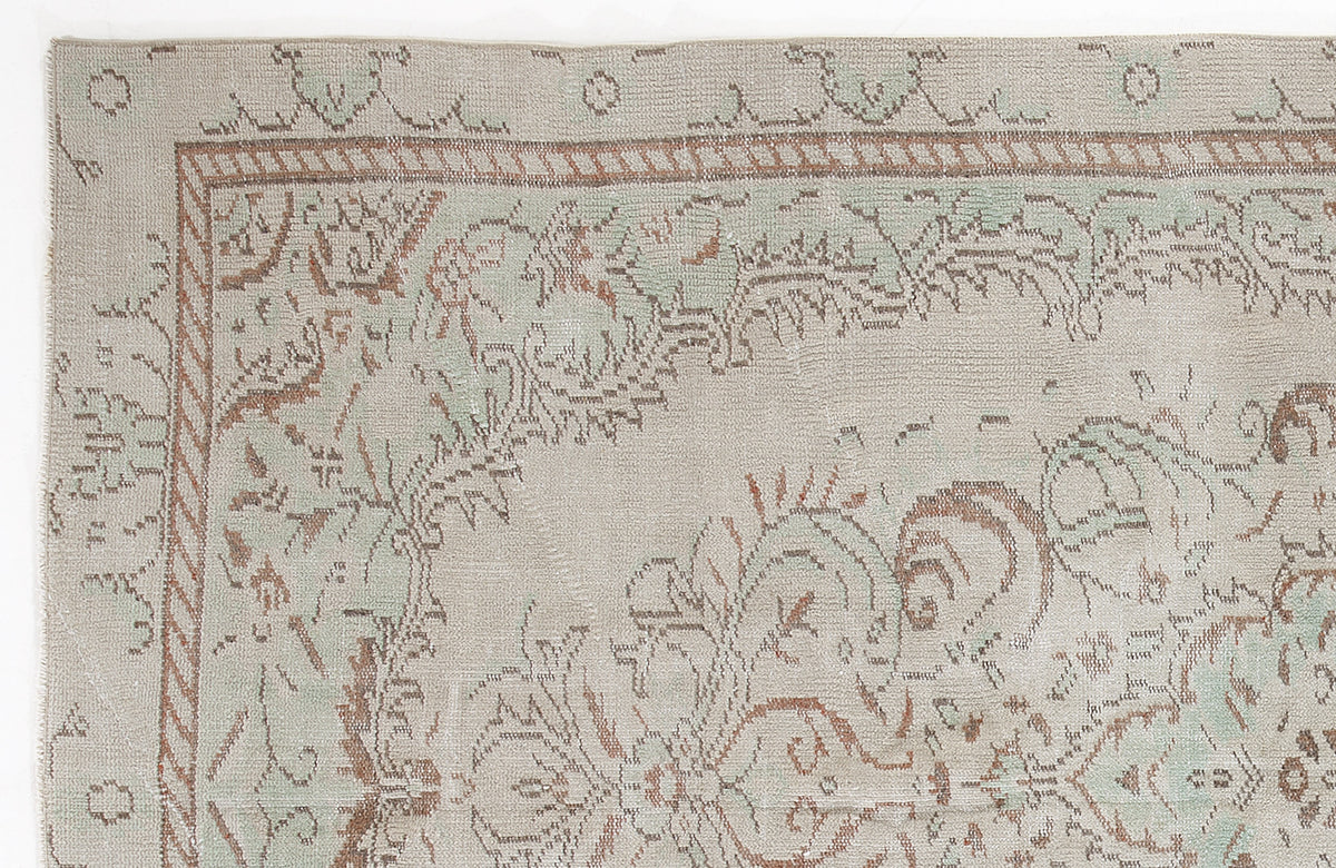 Beige, sage green, and terracotta rug with a distressed traditional floral border and medallion pattern.