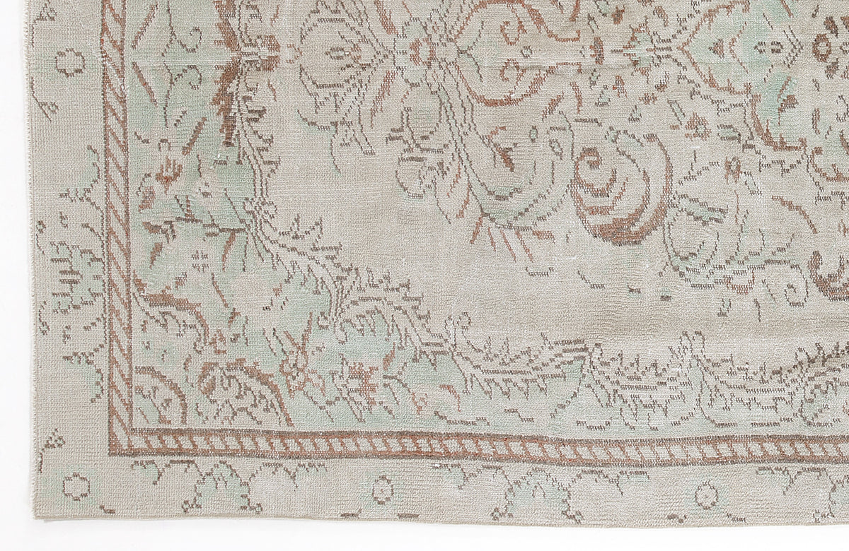 Beige and sage green rug with a distressed traditional floral medallion pattern and a rope-style border.