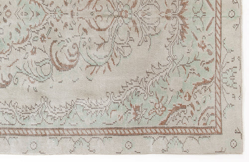 Load image 1 in gallery view. Beige rug with a distressed floral medallion pattern in sage green and terracotta, featuring a braided border.
