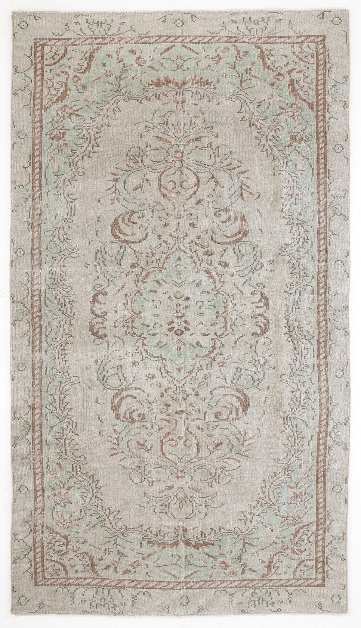 Beige rug with a faded sage green and terracotta floral medallion pattern and a decorative border.