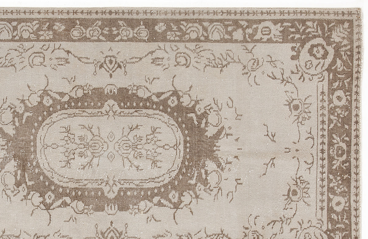 Taupe and beige traditional rug with a distressed floral medallion pattern and a decorative border.