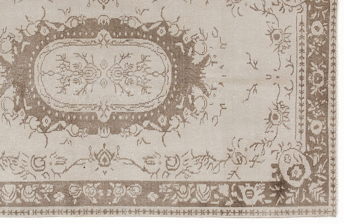 Beige and taupe vintage-style rug with a distressed floral medallion pattern and a decorative border.