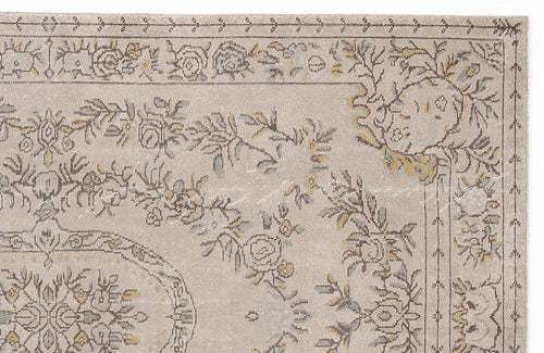 Load image 1 in gallery view. Beige rug with a distressed floral medallion pattern in muted grey and mustard yellow, isolated on a white background.