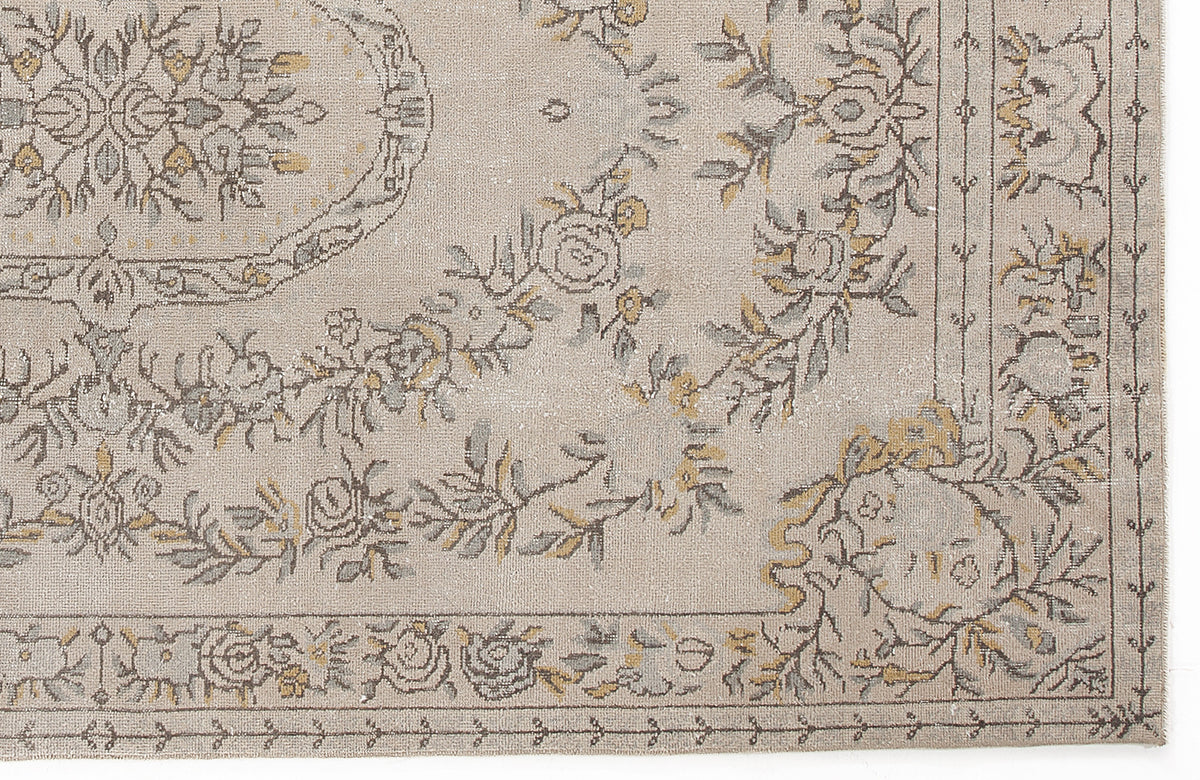 Beige rug with a grey and mustard yellow floral medallion pattern and a decorative border.