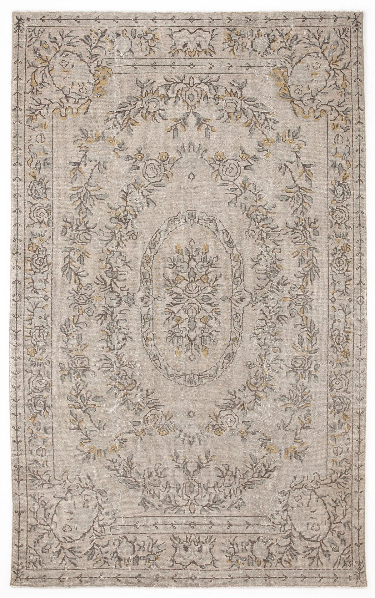 Beige rug with a distressed floral medallion pattern in grey and muted yellow, featuring a decorative border.