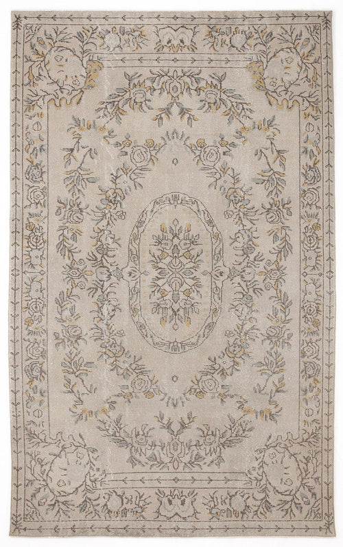 Load image 1 in gallery view. Beige rug with a distressed floral medallion pattern in grey and muted yellow, featuring a decorative border.