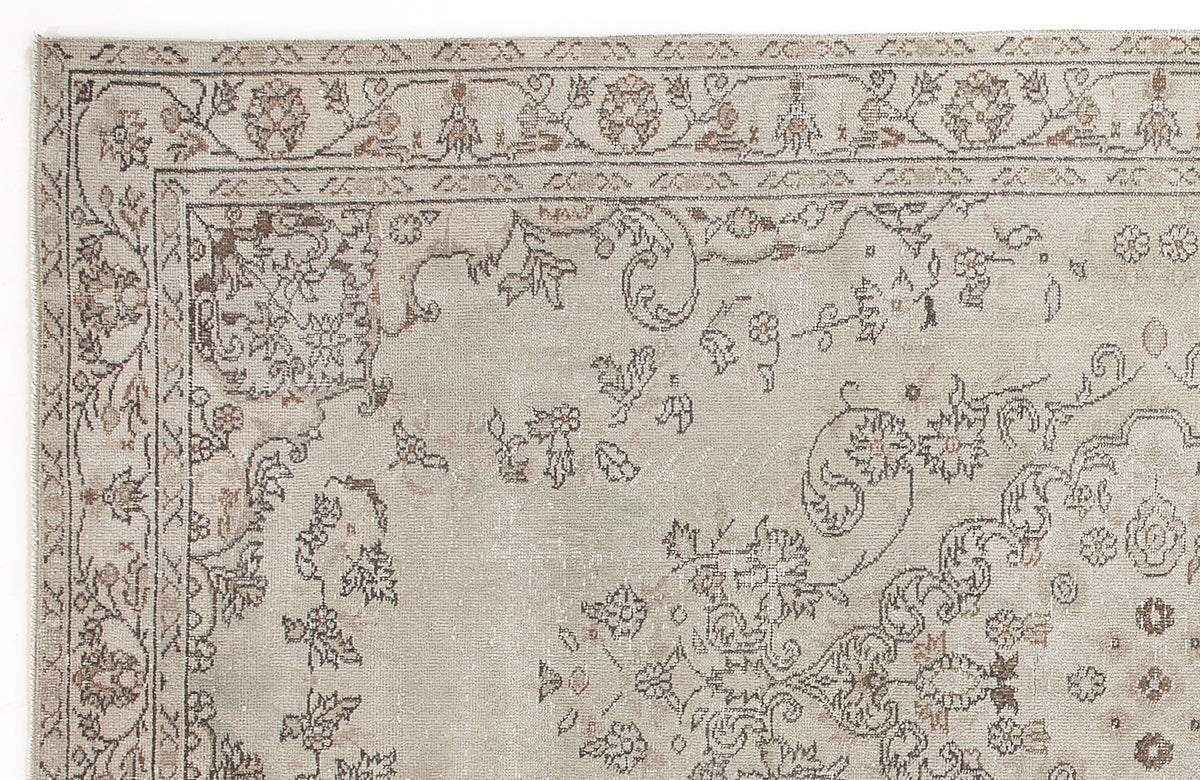 Beige and taupe distressed area rug with a traditional floral medallion border and intricate botanical motifs.