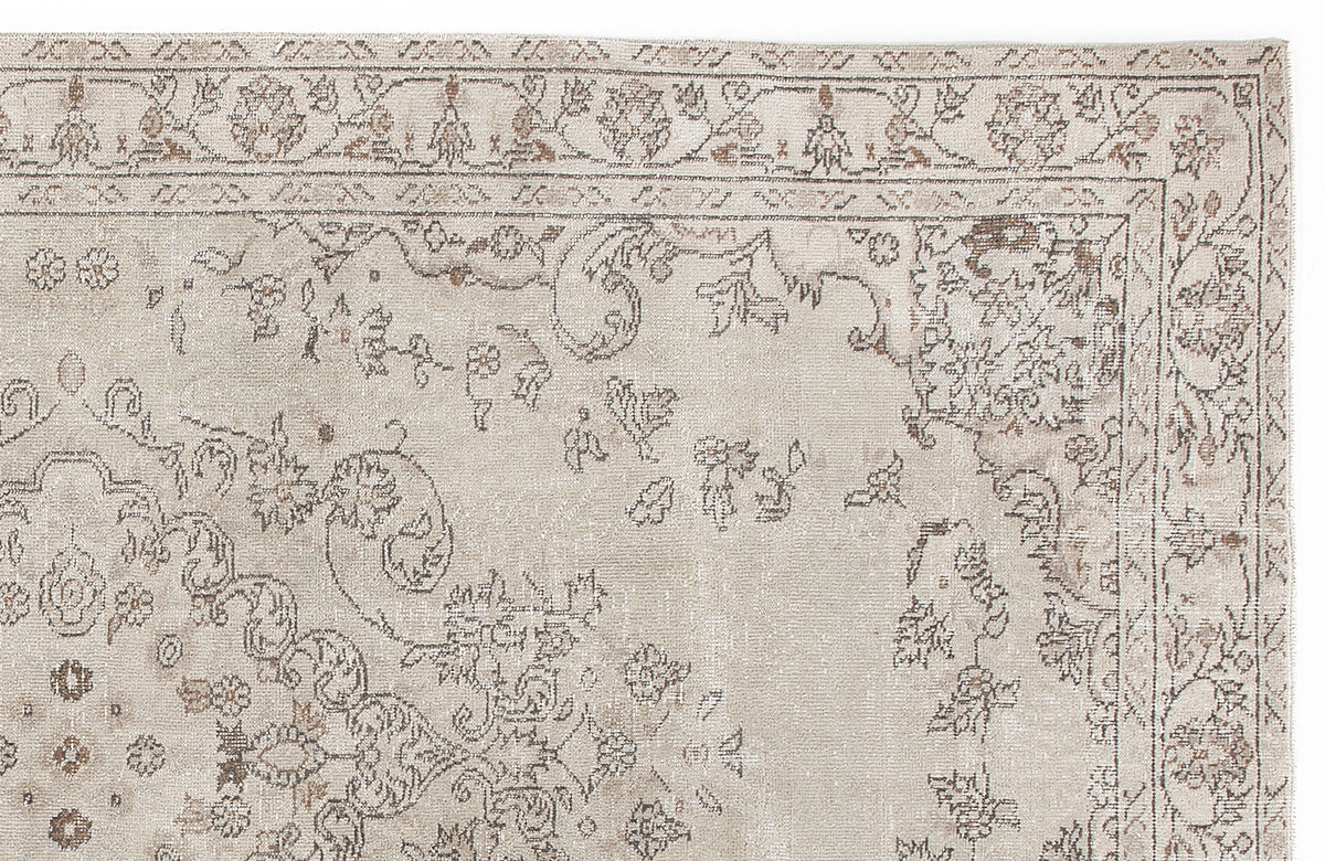 Beige and taupe traditional rug with a distressed floral medallion pattern on a white background.