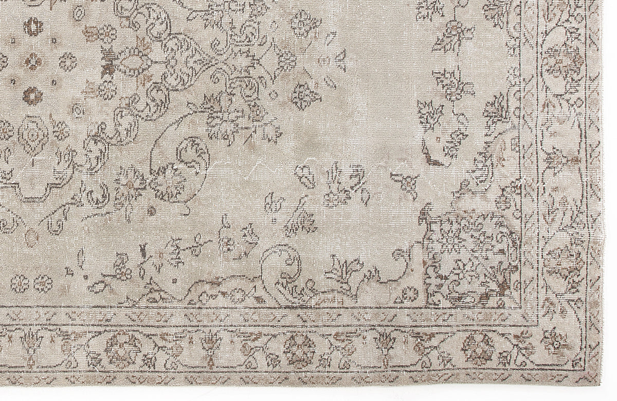 Beige and taupe distressed rug with a faded traditional floral medallion pattern and a decorative border.